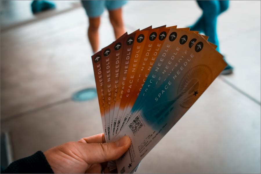 a human hand holding approximately 10 paper event tickets